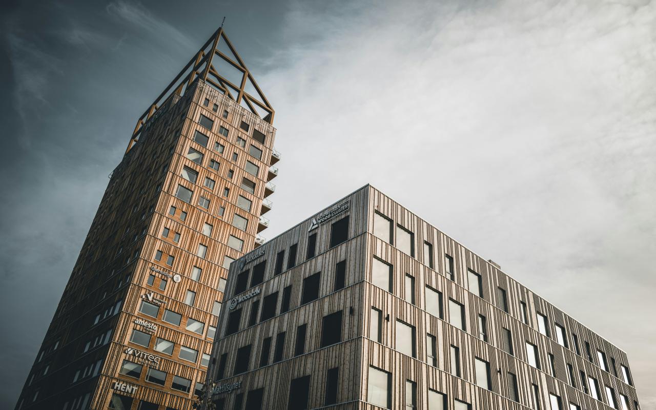 Gedung pencakar langit modern menjangkau ke arah langit berawan.