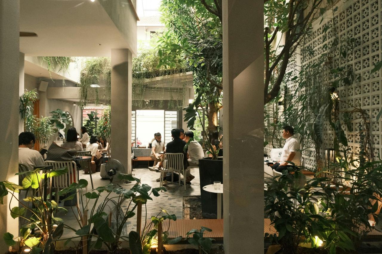 Orang-orang bersantap di kafe modern yang subur dengan tanaman.